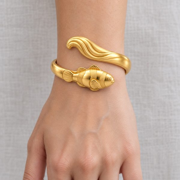 Gold-tone clownfish bangle with raised fish and wave details