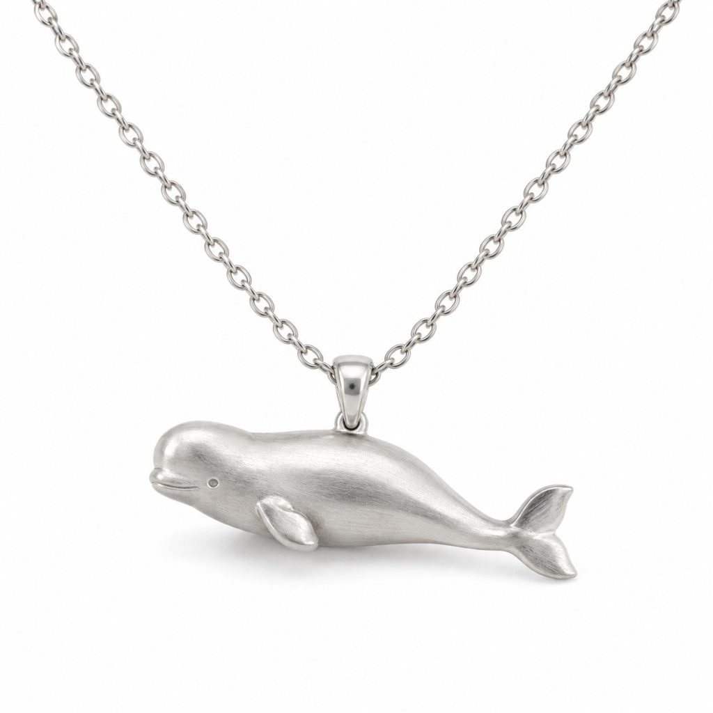Silver-tone beluga whale pendant necklace with a rounded forehead, textured body and oval-link chain on a white background