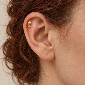 Miniature gold-tone squid stud worn vertically in the upper ear