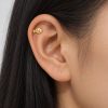 Small gold-tone clownfish stud worn in the upper ear with long dark hair tucked behind it
