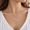 Woman wearing a silver-tone double dolphin pendant on a delicate chain with a white blouse.