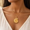 Woman wearing a gold-tone ammonite pendant on a fine matching chain with a cream blouse.
