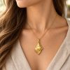Woman wearing a gold-tone conch shell pendant on a delicate matching chain with a beige linen blouse.