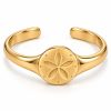 Gold-tone sand dollar open cuff bracelet with a five-petal centerpiece and smooth tapered band on a white background