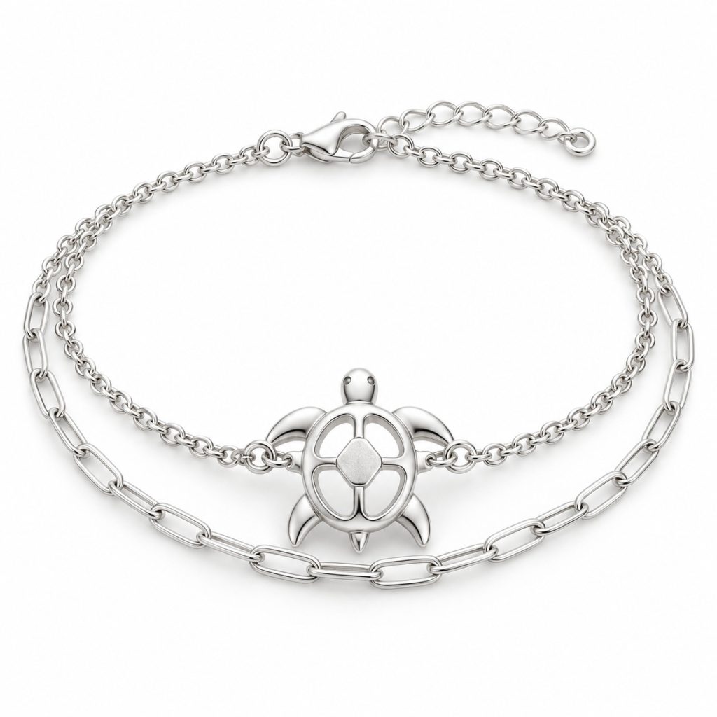 Silver-tone openwork sea turtle bracelet with cable and paperclip-style chains, lobster clasp and extension chain on white