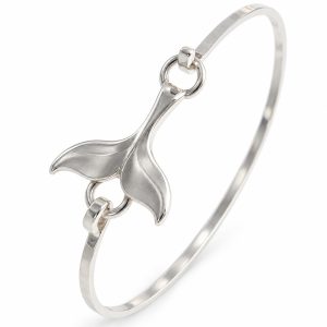 Silver-tone whale tail bangle with sculpted flukes, a slim oval band and hook-and-ring connections on white