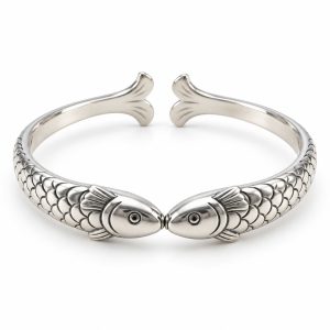 Silver-tone cuff with two fish meeting mouth to mouth, scale-textured bodies and a rear opening between their tails