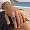 Silver-tone double-curl octopus tentacle ring worn on a finger, showing its spiral ends and textured details
