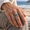 Sculpted silver-tone octopus ring worn on a finger, showing the head and curved tentacle design