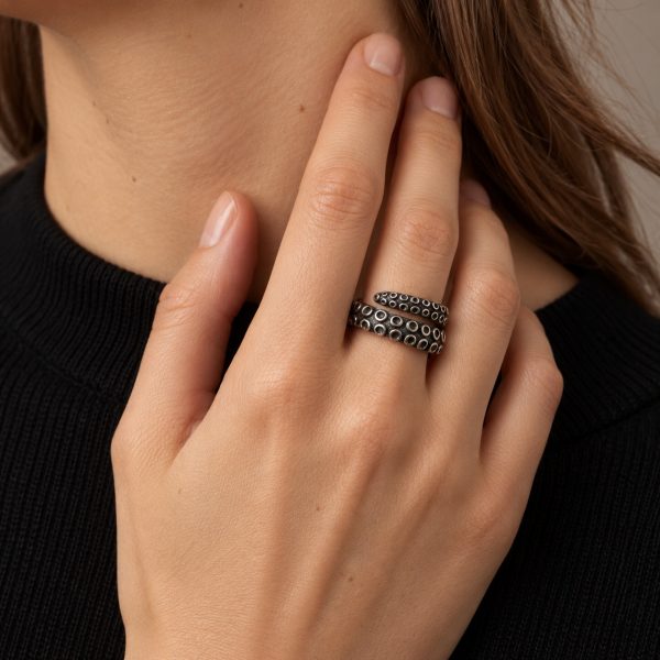 Silver-tone octopus tentacle wrap ring worn on a finger, showing its overlapping band and sucker details