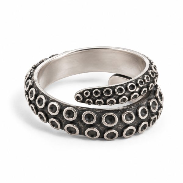 Silver-tone octopus tentacle wrap ring with overlapping ends and circular sucker details on white